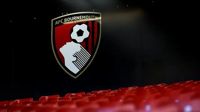 Bournemouth's badge against a black wall with stadium seats in the foreground