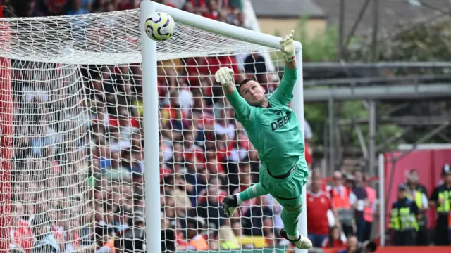 Sam Johnstone, wearing Wolves' green goalkeeping kit, dives up to his right as the ball goes past the post at Nottingham Forest.