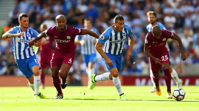 Tomer Hemed of Brighton and Hove Albion chases the ball under pressure from Fernandinho and Vincent Kompany of Manchester City during a Premier League match