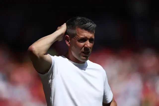 Paulo Pezzolano, wearing a white t-shirt, scratches the back of his head.