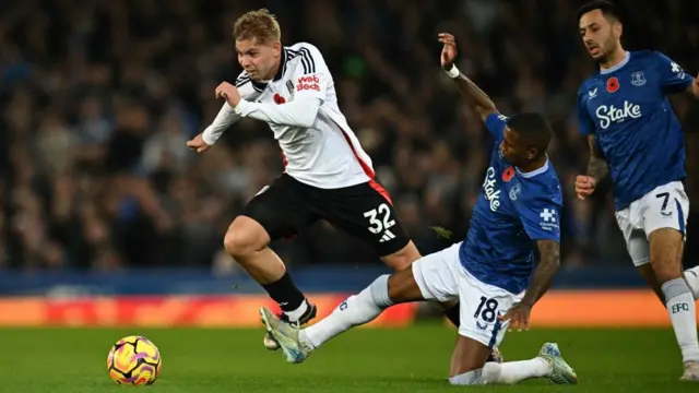 Fulham's English midfielder #32 Emile Smith Rowe (L) jumps over a challenge from Everton's English defender #18 Ashley Young (C) during the English Premier League football match between Everton and Fulham at Goodison Park