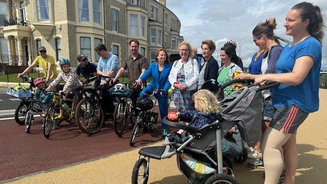 A group of people standing around with prams and bikes