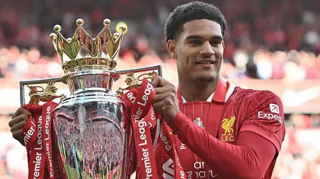 Jarrell Quansah holds the Premier League trophy in his Liverpool kit at Anfield