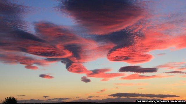 Several lens shaped clouds with a pink hue
