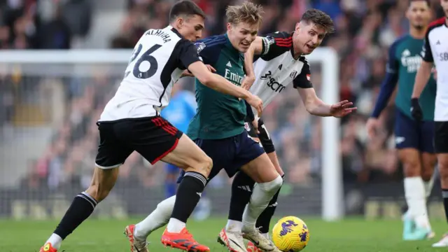 Odegaard is challenged by Cairney and Palhinha