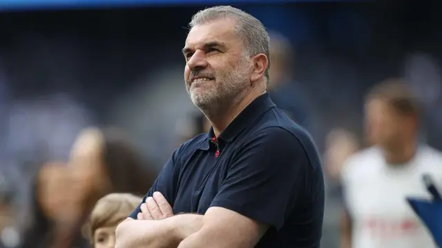 Ange Postecoglou smiles with arms crossed