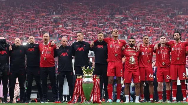 Liverpool players and staff with the Premier League trophy and winners medals