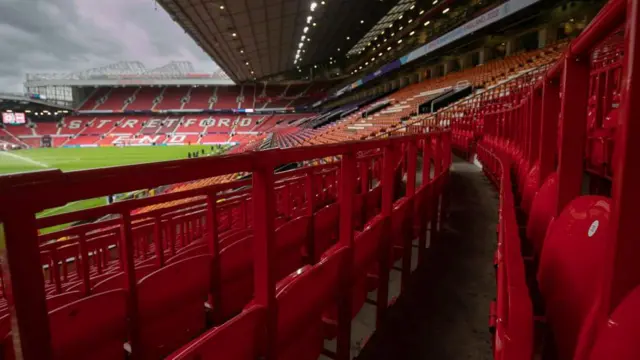 Safe standing seats at Old Trafford  in the foreground. The stadium in the background with the pitch visible.