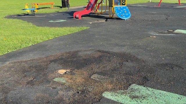 A close-up of a scorched section of ground in Cocker Beck playground where a now removed timber playframe stood before the arson attacks.