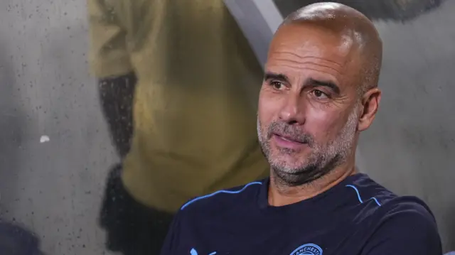 Pep Guardiola sits in the dugout