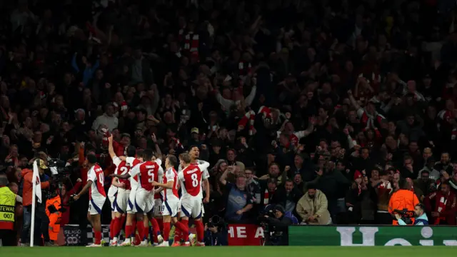 Arsenal players celebrate goal in front of fans