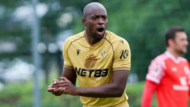 Jean-Philippe Mateta rubs his hands wearing Crystal Palace's new gold strip