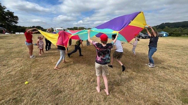 Lluniau o blant yn chwarae gyda parachute 