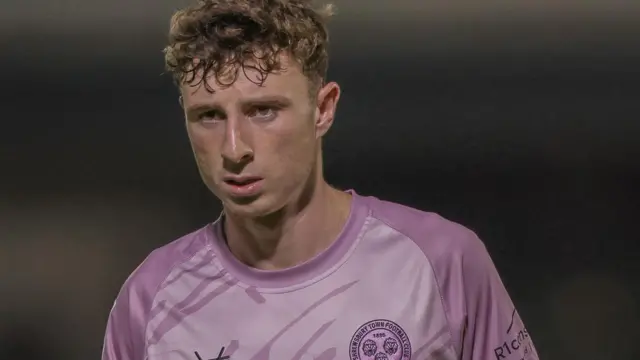 Shrewsbury Town striker Callum Stewart. He is wearing a pink away shirt.