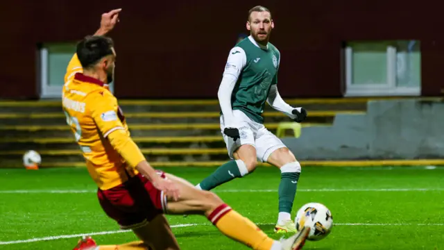 Hibernian's Martin Boyle (R) takes a shot but it's blocked by Motherwell's John Koutroumbis