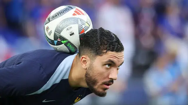 Rayan Cherki warms up with the ball balanced on his neck