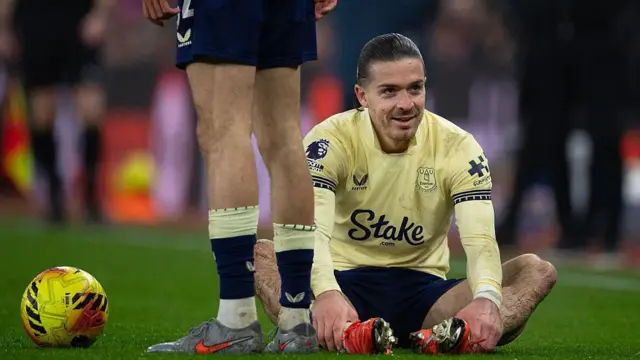 Jack Grealish sits on the pitch