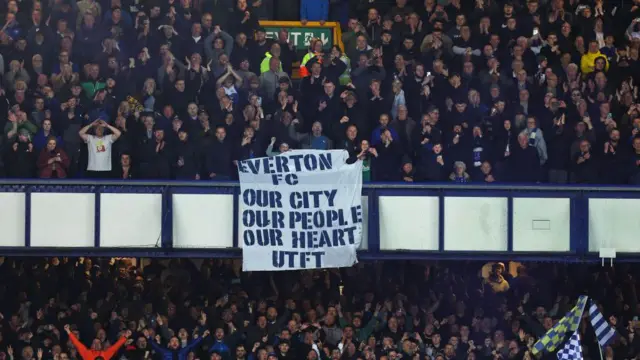 Fans of Everton hold up a banner