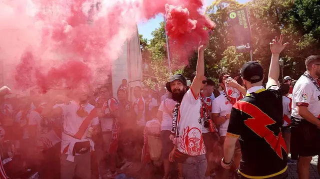 A Rayo Vallecano fan lets off a pyro cannister to release red smoke