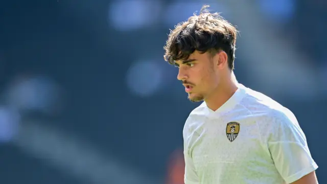 Olly Tipton warms up for Notts County wearing a white tee shirt with the club's badge on it.