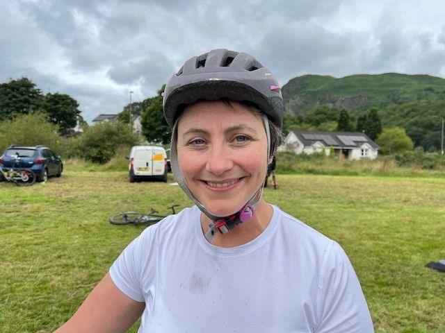 Judith McVinnie in a white t-shirt and grey cycling helmet 