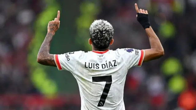 An image that shows the back of Luis Diaz with his fingers pointing to the sky