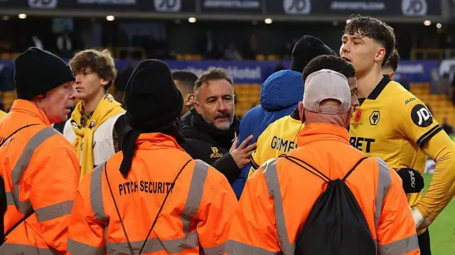 Wolves boss Vitor Pereira and striker captain Jorgen Strand Larsen surrounded by pitch security after arguing with supporters after their defeat by Burnley