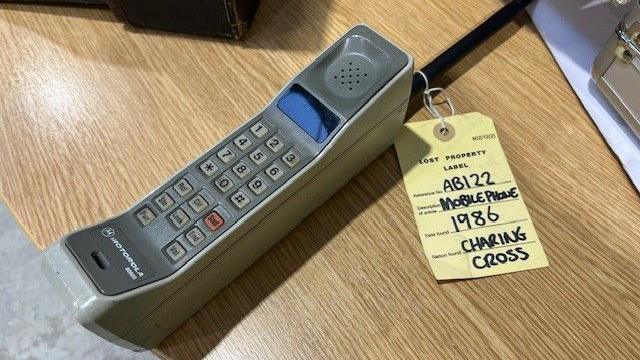 Old mobile phone with yellow tag attached by TfL saying found in Charing Cross in 1986 