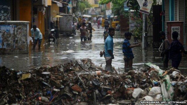 People stand in a flooded street in Chennai