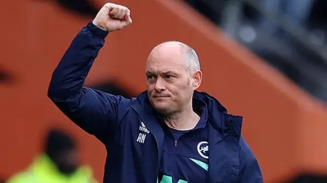 Millwall boss Alex Neil raises his right arm in celebration of another win.