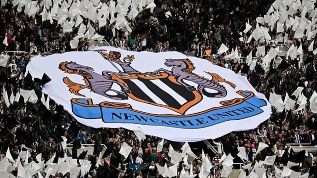 Newcastle United supporters wave a banner depicting the club crest