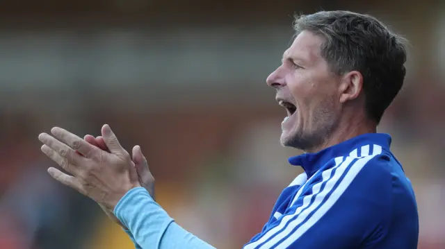 Oliver Glasner applauds wearing a blue tracksuit top