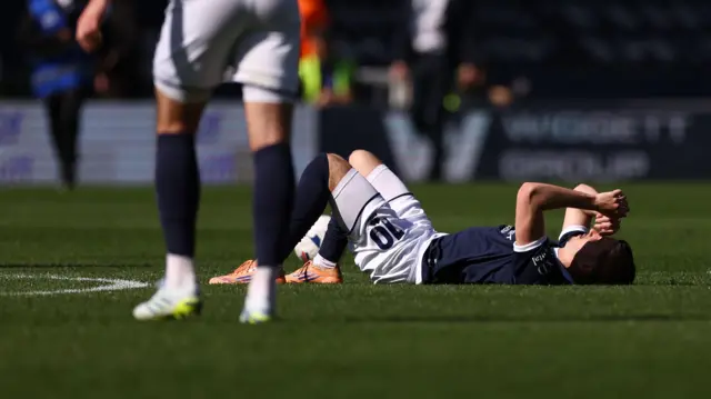 Camiel Neghli lies on the floor wearing his dark blue Millwall home kit after a disappointing loss to Norwich City