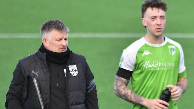 Guernsey FC boss Tony Vance with a player after the match on the pitch.