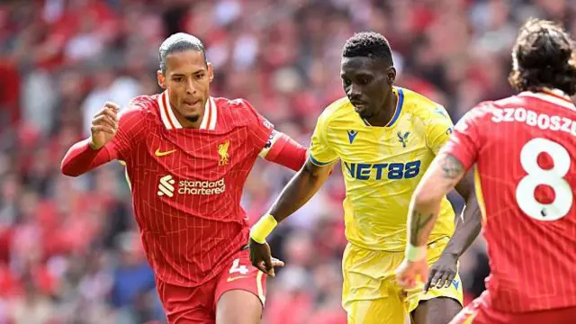 Ismaila Sarr of Crystal Palace is challenged by Virgil van Dijk and Dominik Szoboszlai of Liverpool during a Premier League match at Anfield 