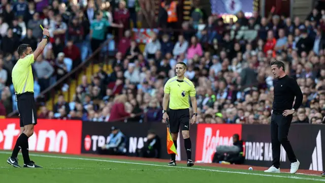 Referee Andy Madley shows a yellow card to Fulham head coach Marco Silva