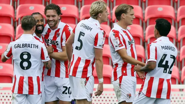 Stoke City's players, wearing their red and white home shirt with white shorts, celebrate in a group after scoring in the EFL Cup against Oldham. 