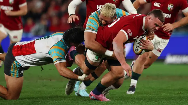 First Nations and Pasifika XV players tackle Ben Earl of the British and Irish Lions