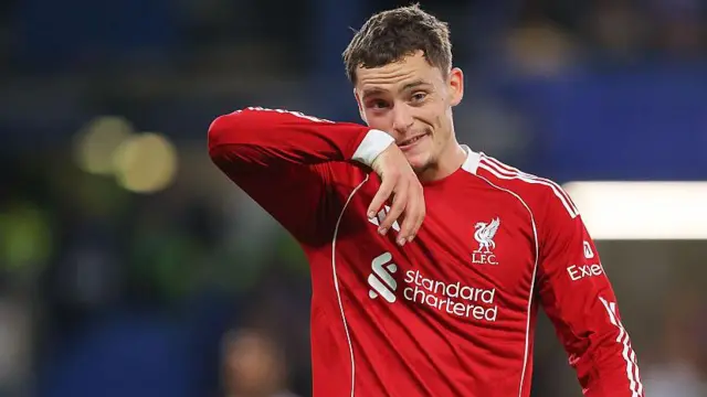 Florian Wirtz, wearing Liverpool's red home shirt, wipes his face with his sleeve during a match