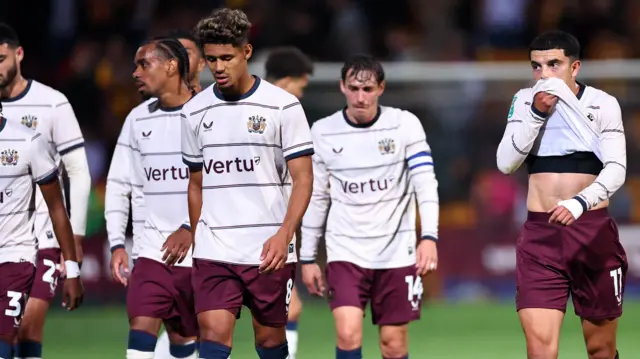 Burnley players, wearing their white away shirt with claret shorts, look dejected after the penalty shootout defeat to Bradford City in the Carabao Cup