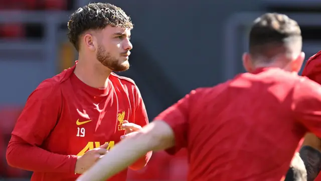 Harvey Elliott looking pensive while warming up in a Liverpool training top