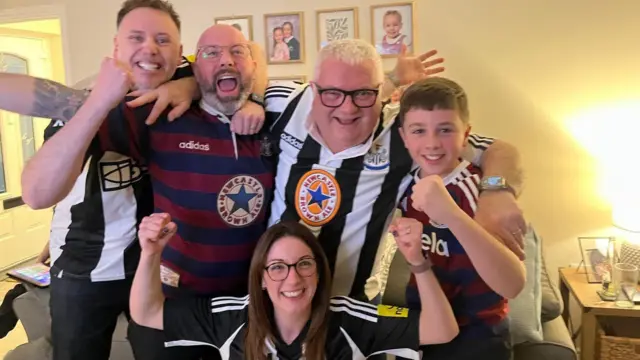 Family dressed in Newcastle shirts celebrating.