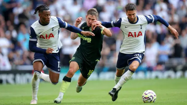 Yehor Yarmolyuk of Brentford is challenged by Destiny Udogie and Rodrigo Bentancur of Tottenham Hotspur during the Premier League match between Tottenham Hotspur FC and Brentford FC at Tottenham Hotspur Stadium