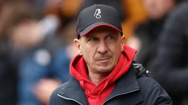 Gerhard Struber in the City technical area wearing a Robins cap