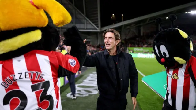 Thomas Frank high fives Brentford mascot Buzzette