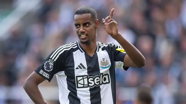 Alexander Isak stands in the famous black and white Newcastle kit
