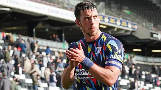 Niall Canavan, in Barrow's multi-coloured shirt, applauds fans as he leaves the field.