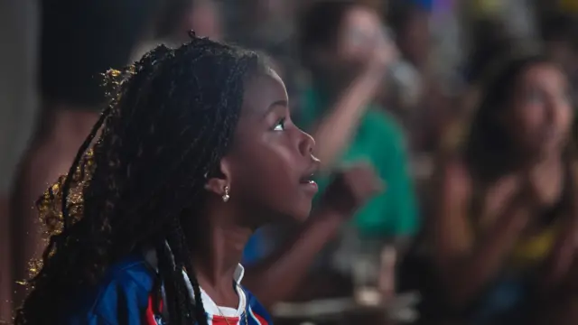A child football fan looks on in wonder as she watches a match