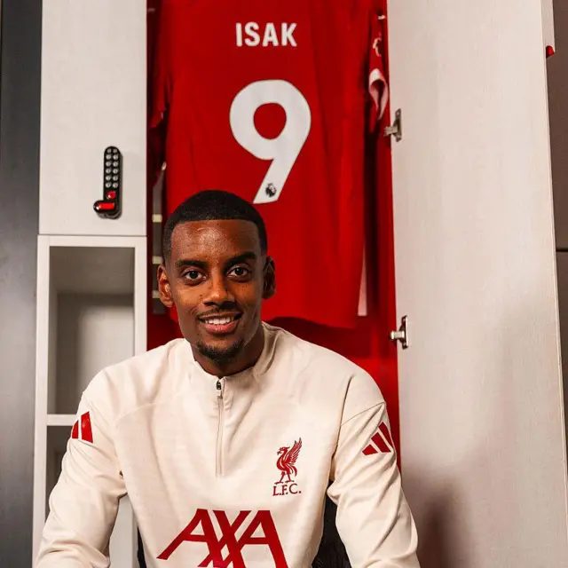 Alexander Isak in white Liverpool jacket in front of a number nine shirt