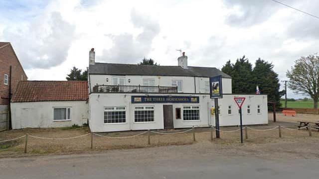 A white building with The Three Horseshoes sign above the door